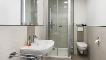 A modern bathroom with a glass-enclosed shower, a white sink, and a toilet.