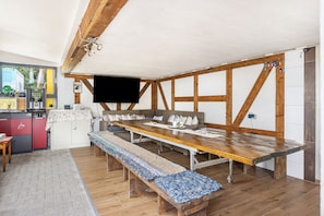 Ein Essbereich mit einem langen Holztisch, Bänken und einem an der Wand befestigten Fernseher.