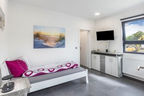 Ein modernes Zimmer mit einer Sitzbank, einem Flachbildfernseher, einem Fenster mit Blick auf eine Baustelle und einem Wandbild.