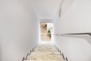 Una escalera con escalones de mármol que conduce a una habitación con cama y ventana.