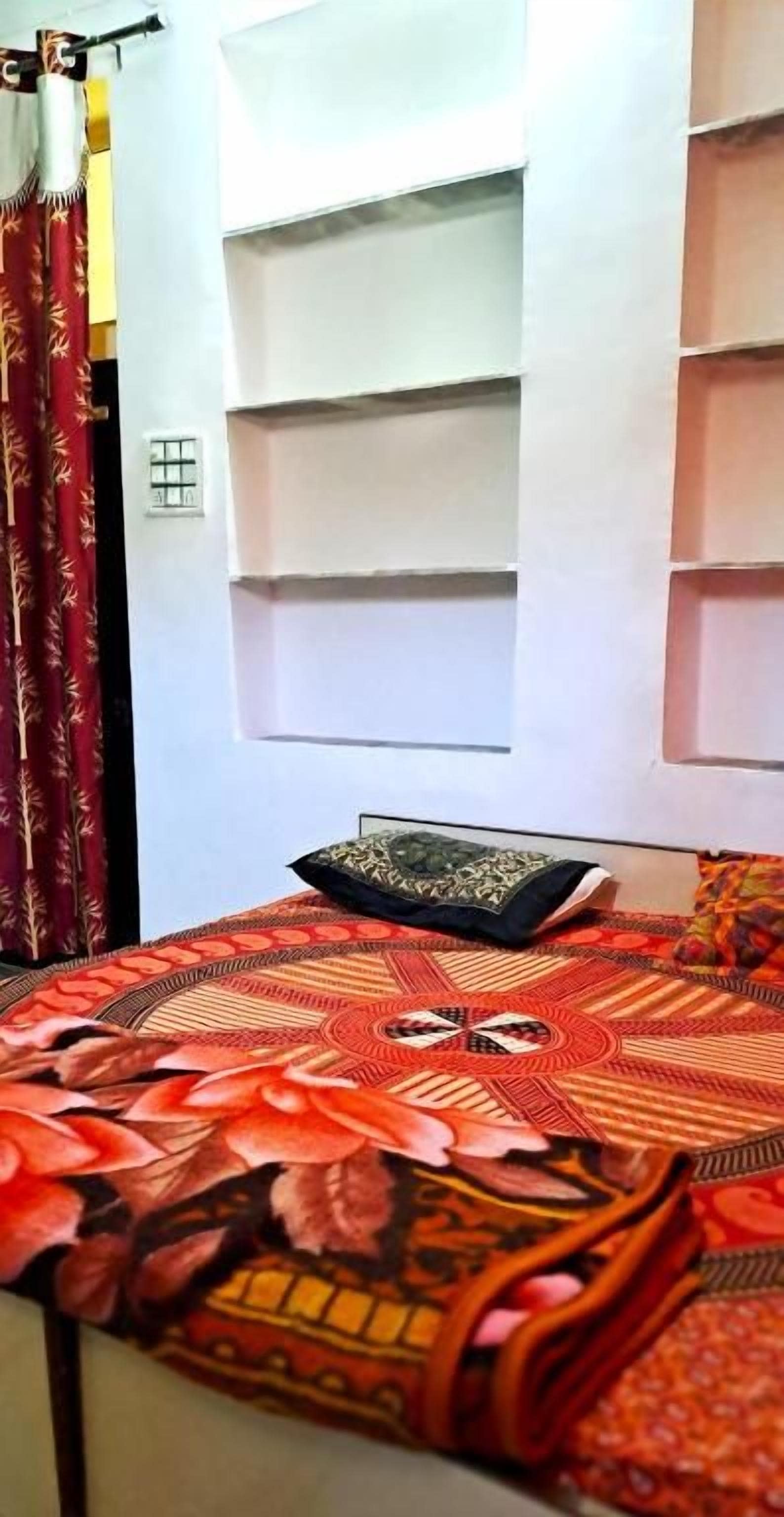 Un letto con una coperta a motivi, un cuscino e una mensola a muro.