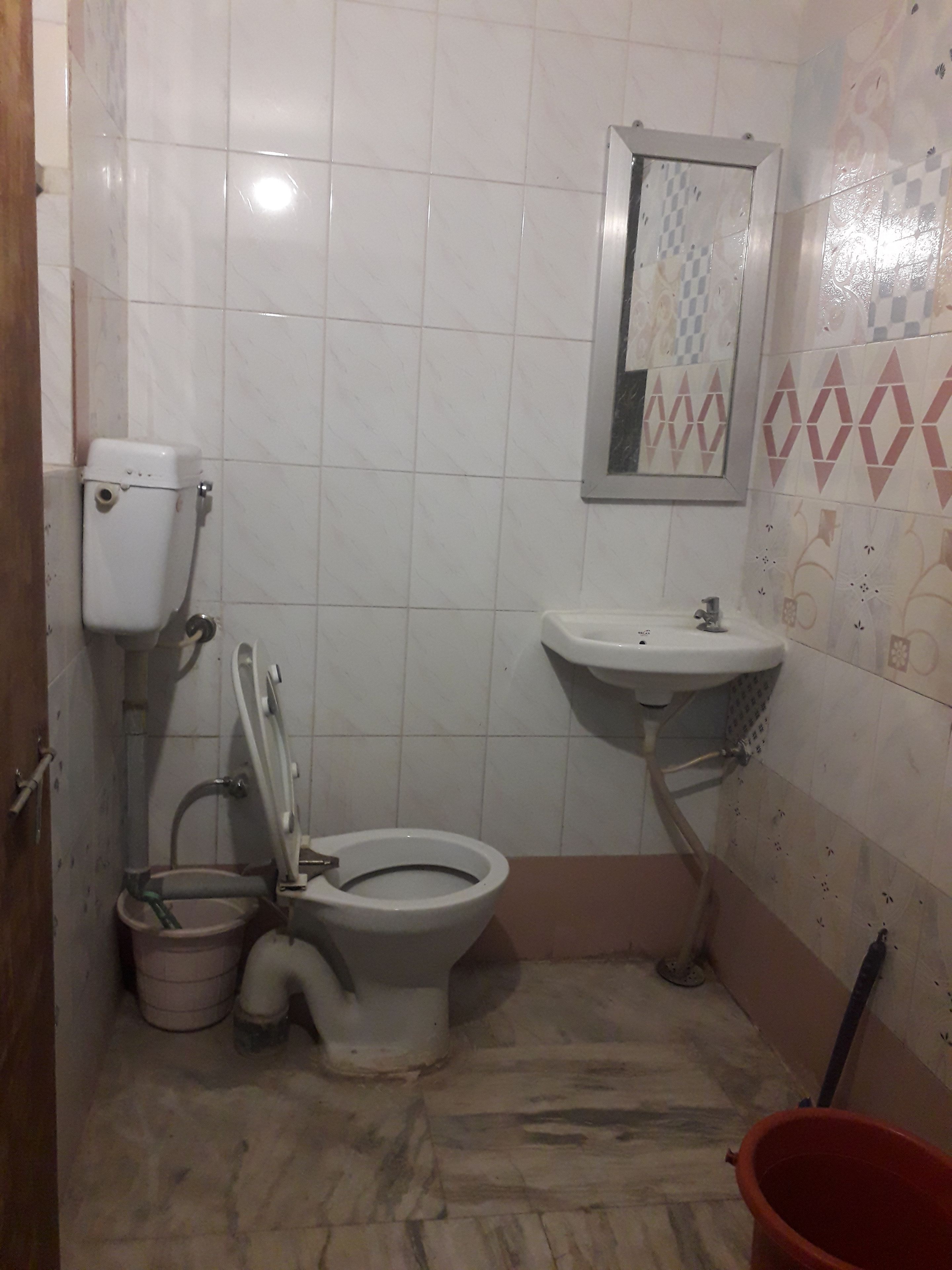 A small bathroom with a toilet, sink, and a mirror.
