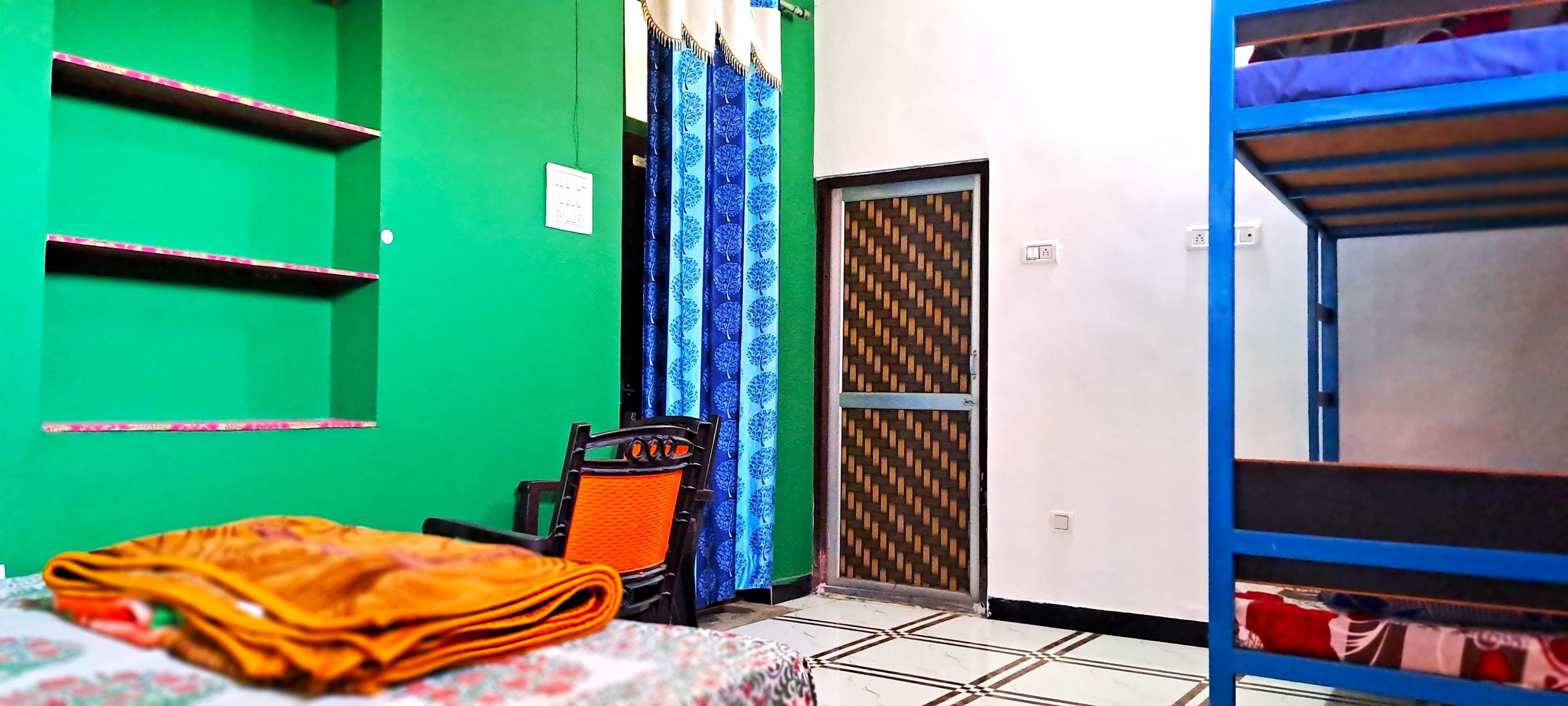 Una habitación con una cama, una silla, una mesa y un armario. Hay una puerta con un diseño decorativo y una ventana con cortinas.