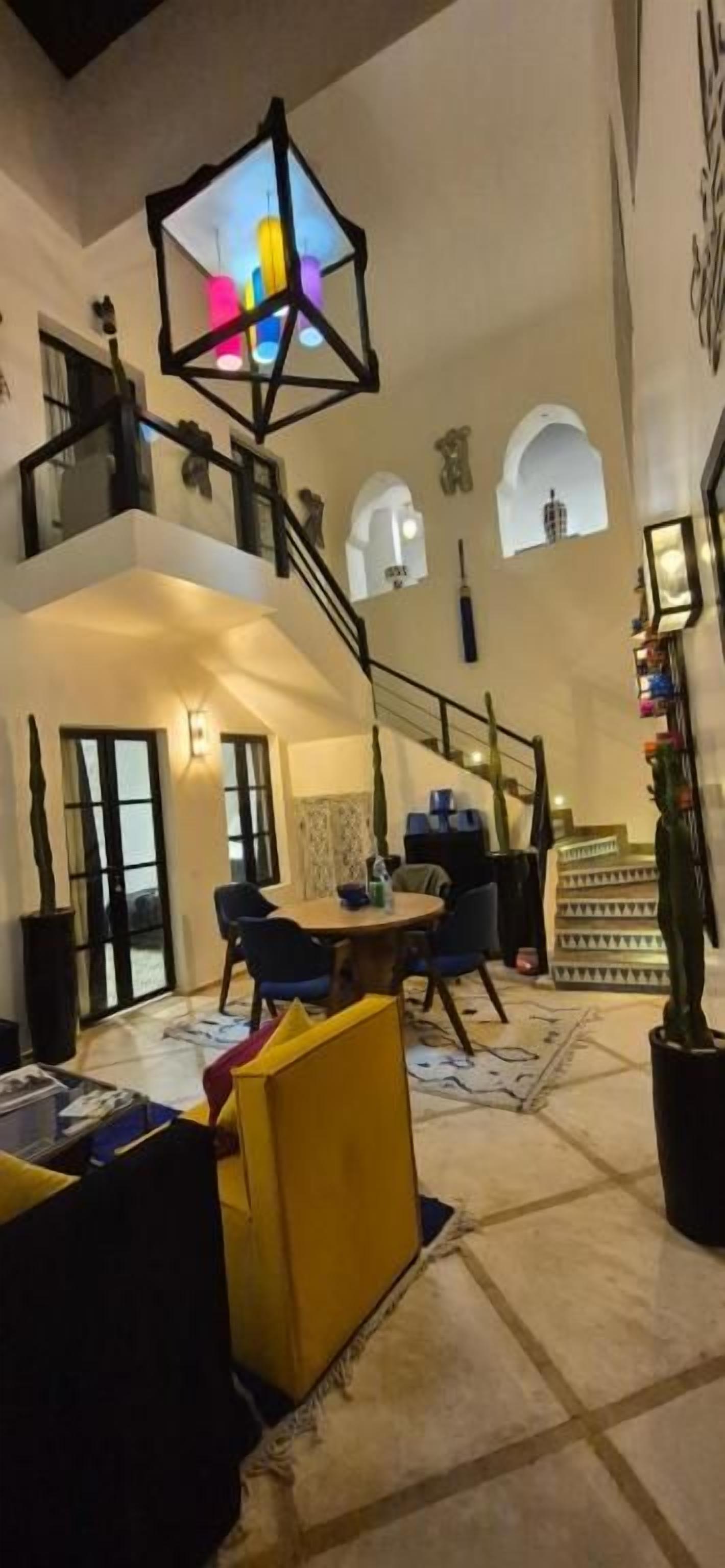Un interior espacioso con escalera, zona de estar y una lámpara decorativa.