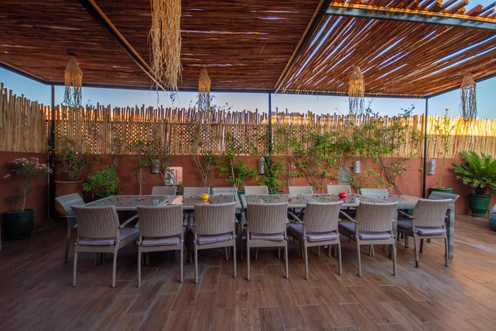 Un patio exterior con cerca de bambú, mobiliario de mimbre y plantas en macetas.