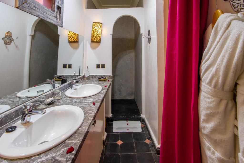Un baño con dos lavamanos, una ducha y un perchero para toallas.