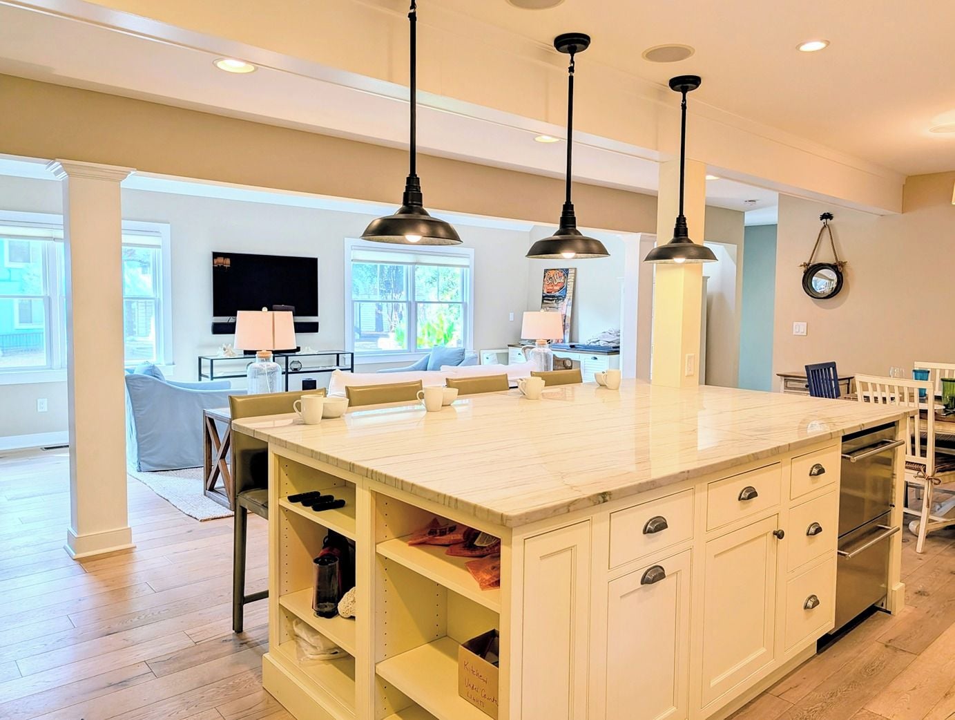 A modern kitchen with a central island, pendant lighting, and built-in shelving.