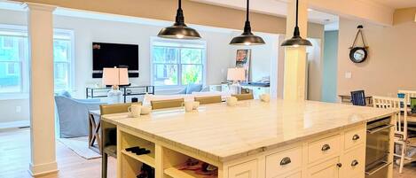 A modern kitchen with a central island, pendant lighting, and built-in shelving.