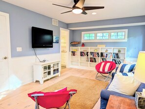 Een woonkamer met een flatscreen televisie, een boekenkast, een rode fauteuil en een blauwe bank.