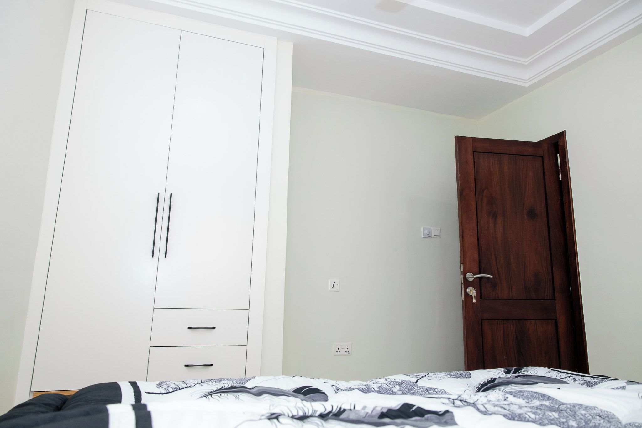 A bedroom with a bed, a wardrobe, and a wooden door.
