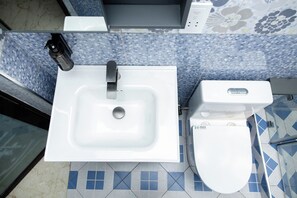 Een badkamer met een witte wastafel, toilet en douche.