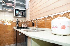 A kitchen with a microwave, stove, sink, and a coffee maker.