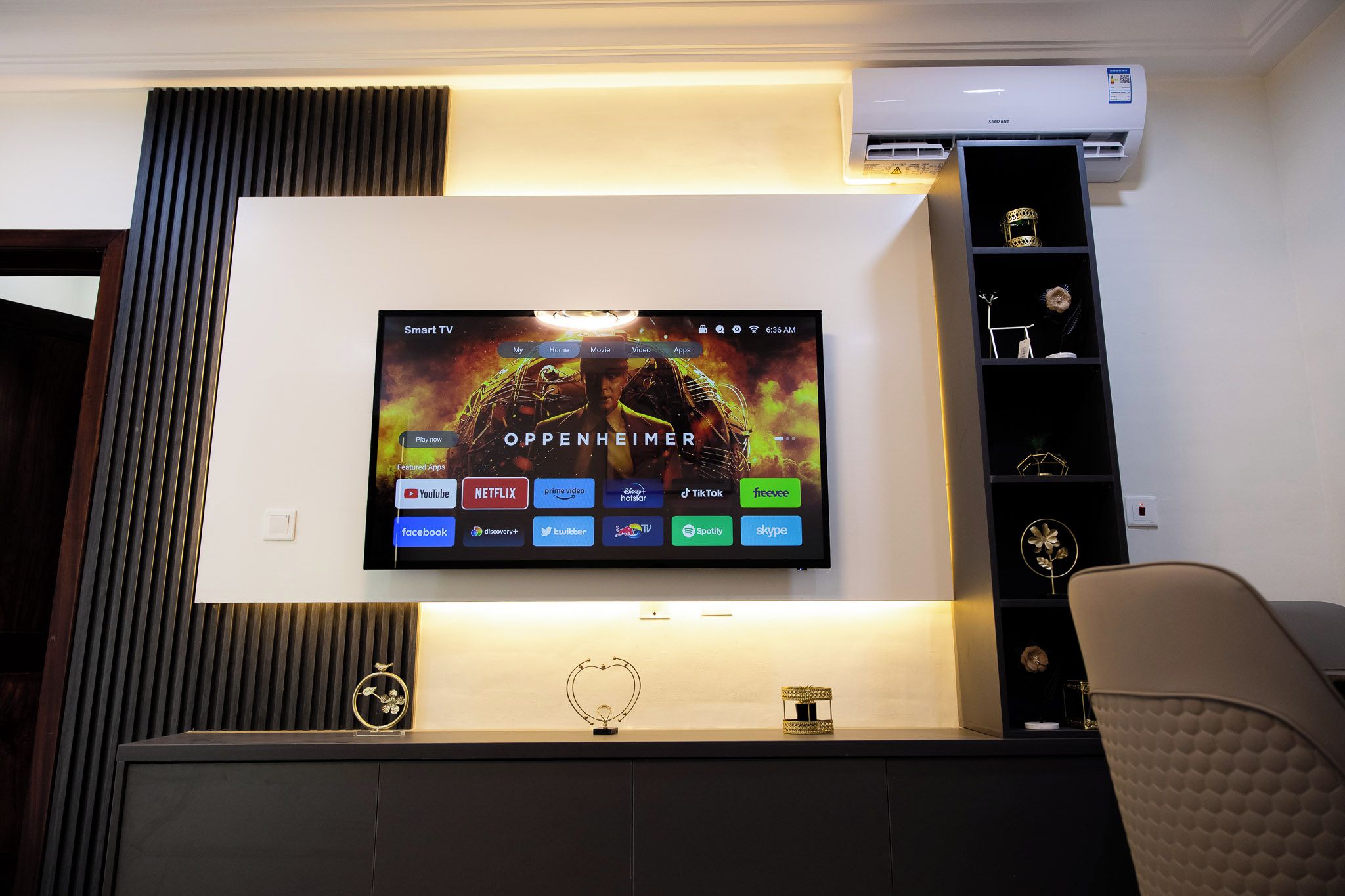 A flat-screen TV mounted on a wall with a Samsung air conditioner above it.
