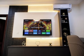 Un televisor de pantalla plana montado en la pared, con un aire acondicionado Samsung encima.