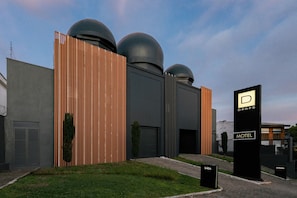 A modern building with a prominent sign for a motel, featuring a minimalist design with vertical wooden slats and spherical structures on top. - Drops Motel Porto Alegre (Porto Alegre)