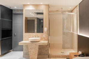 Un baño moderno con un espejo grande, un lavamanos y una ducha.