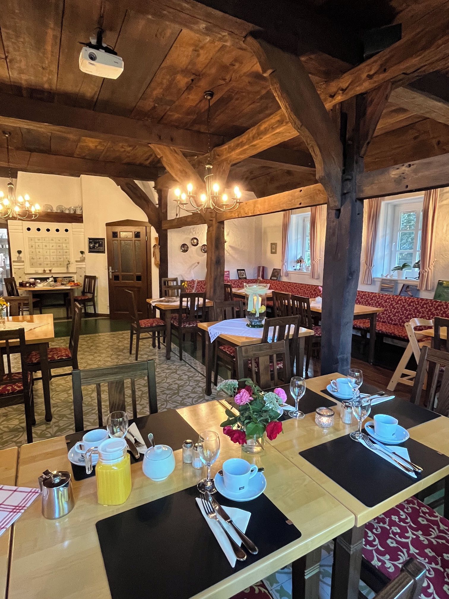 Ein Restaurant mit Holzbalken, gedeckten Tischen und einer Kristallleuchter.