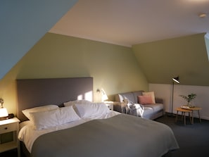 Una habitación de hotel con cama, mesita de noche, lámpara y una pequeña mesa con una planta.