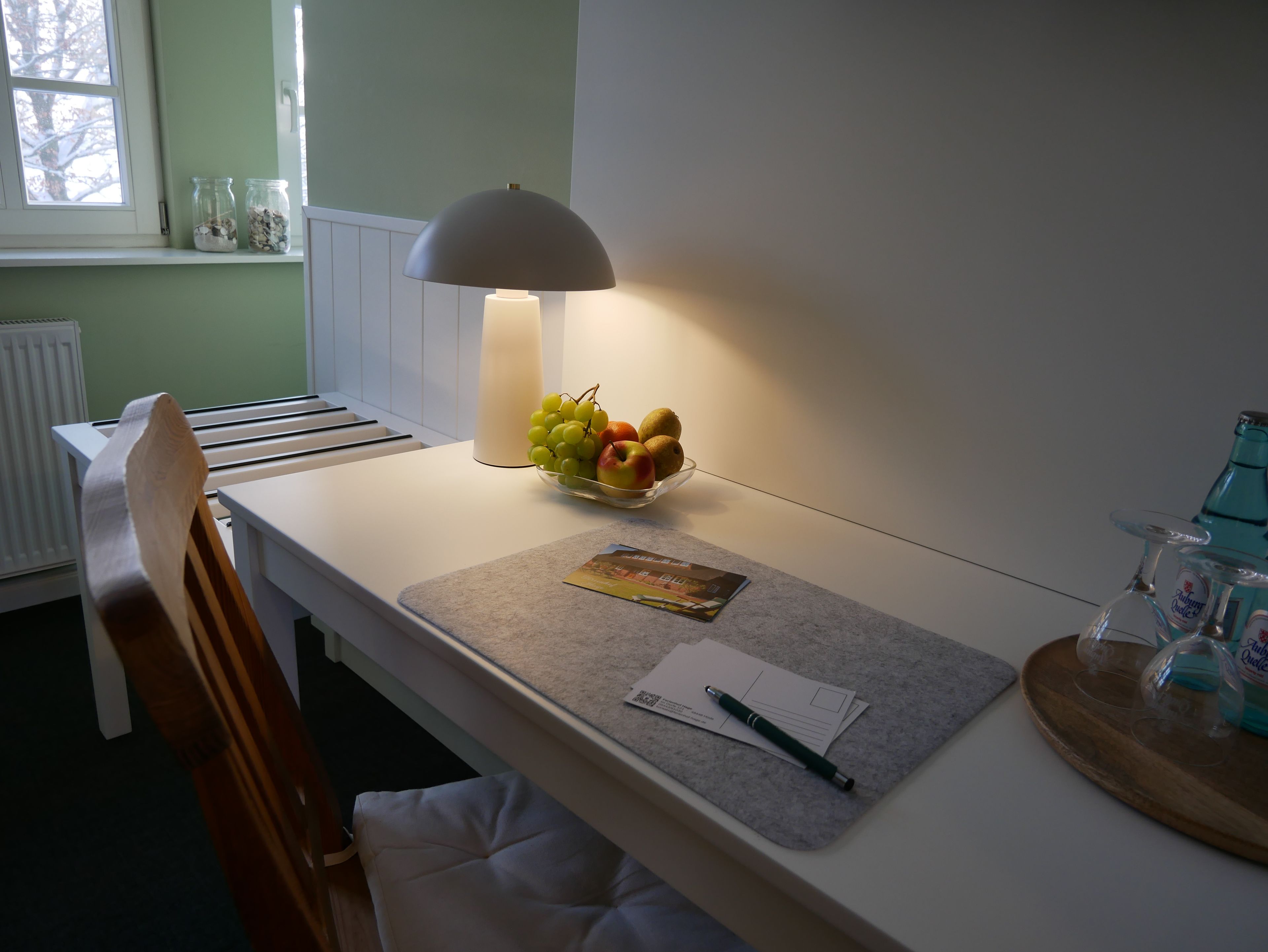 Ein Schreibtisch mit Lampe, Obstschale, Notizbuch und Stift.