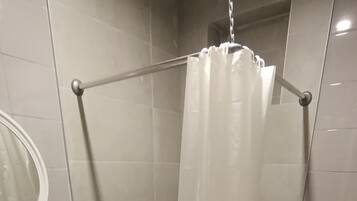 A bathroom with a shower, toilet, sink, and a mirror.