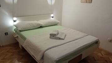 A room with a bed, a wall-mounted light, and a painting.