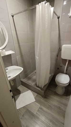 A bathroom with a shower, toilet, sink, and a mirror. - Villa Monera  (Mostar)
