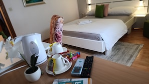A hotel room with a bed, bedside table, a remote control, a kettle, a cup, a plate, a packet of tissues, and a potted plant. - Villa Monera  (Mostar)