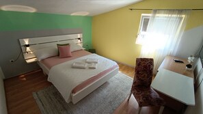 Habitación de hotel con cama, mesita de noche, silla y ventana con cortinas.