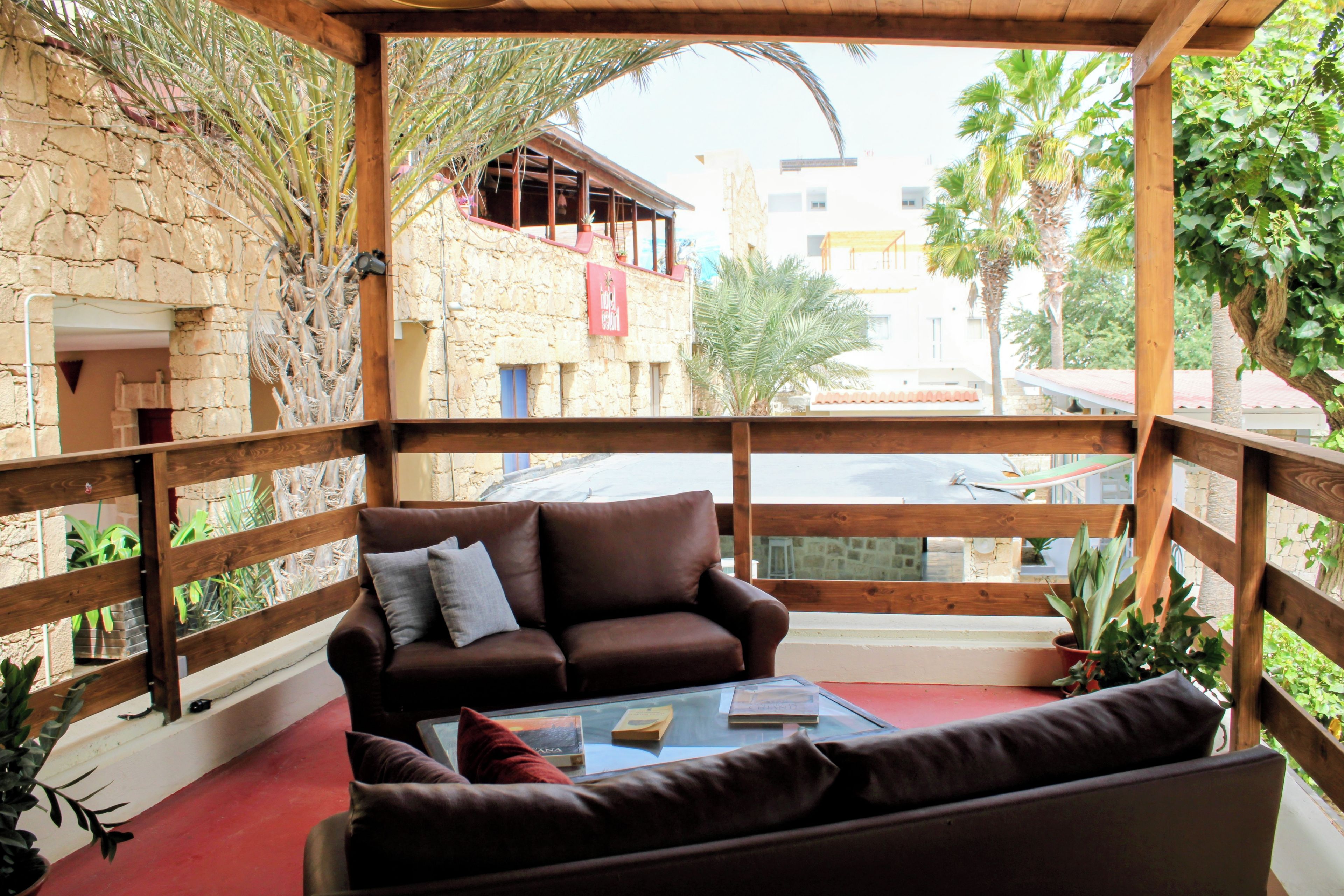 A wooden-framed balcony with a brown leather sofa and a glass coffee table.