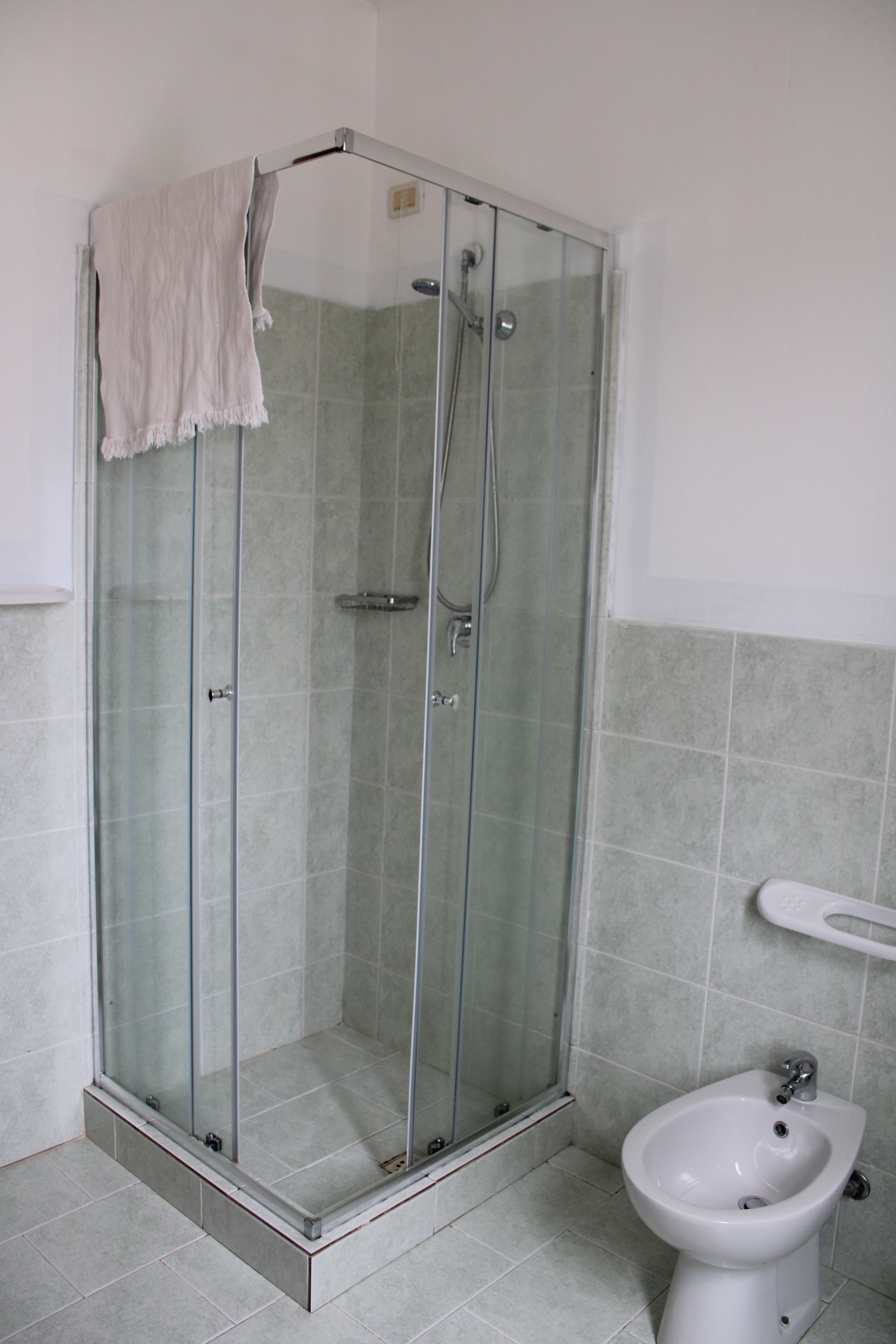 A glass-enclosed shower with a white towel hanging on the door.
