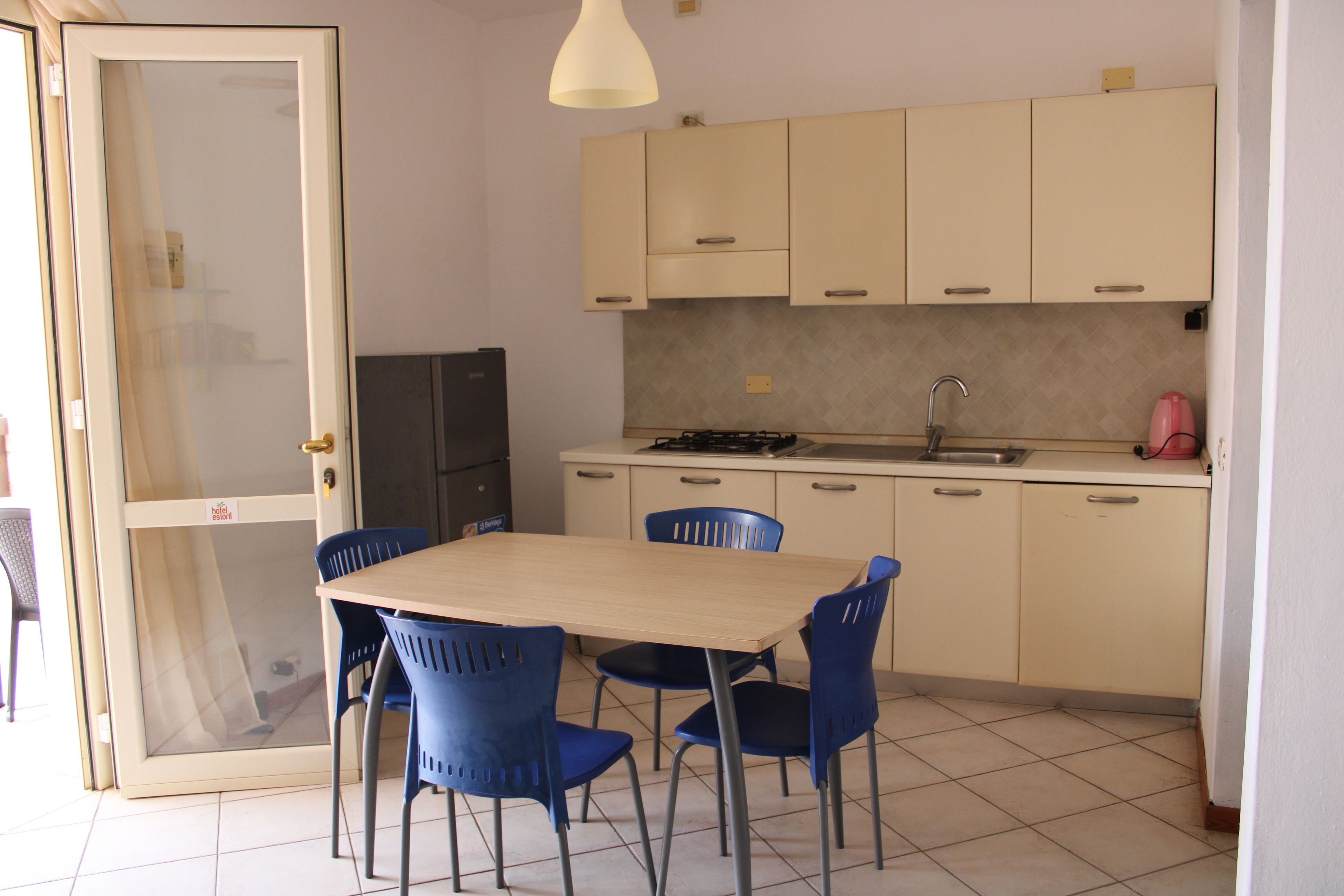 A compact kitchen with a dining table and chairs, a refrigerator, and a sink.