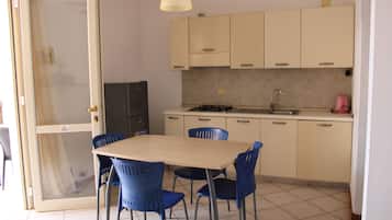 A compact kitchen with a dining table and chairs, a refrigerator, and a sink.