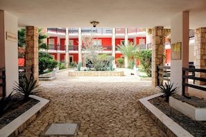 A courtyard with a stone floor, surrounded by red walls and balconies.
