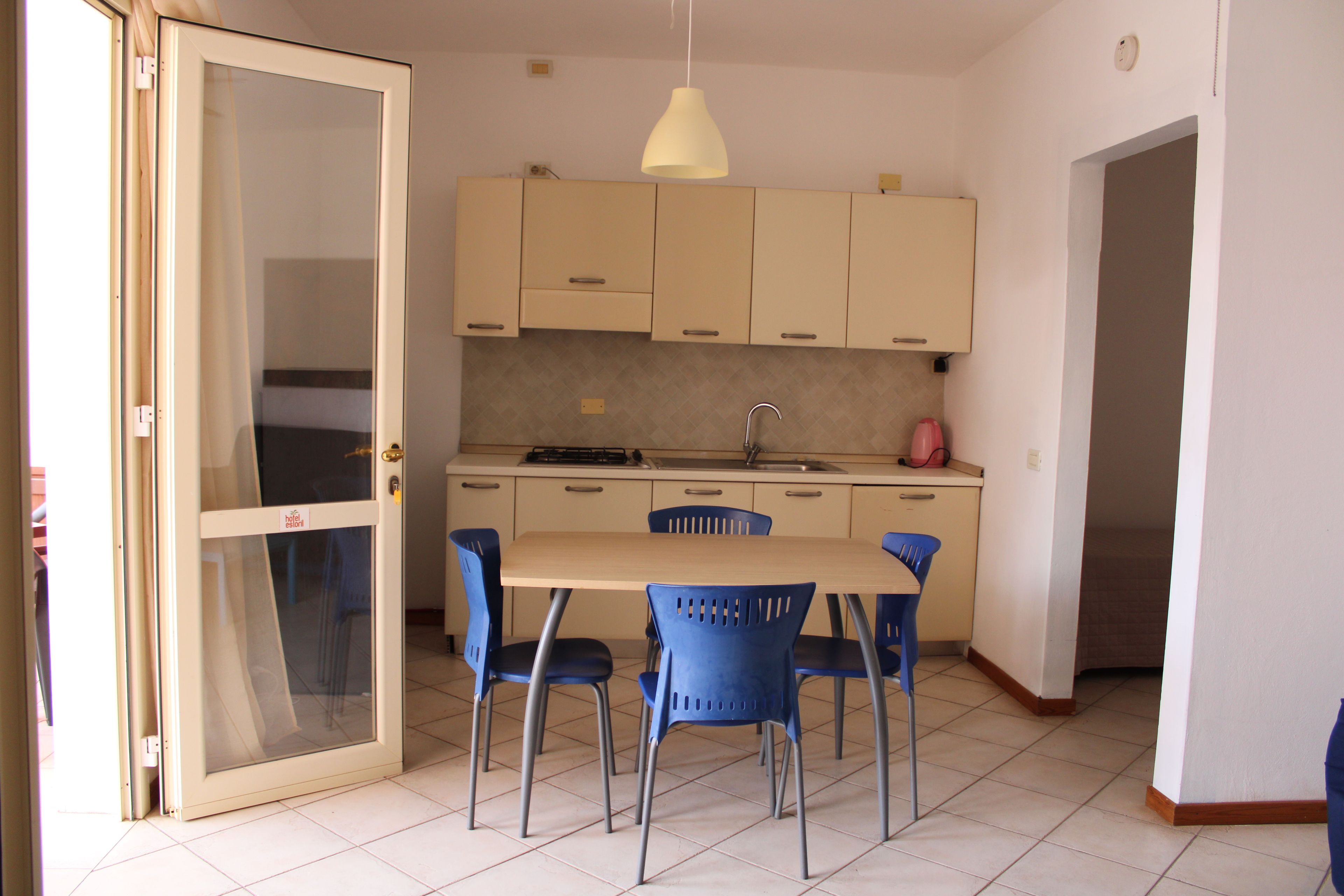 A compact kitchen with a dining table and chairs, a sink, and a stove.