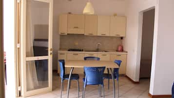 A compact kitchen with a dining table and chairs, a sink, and a stove.