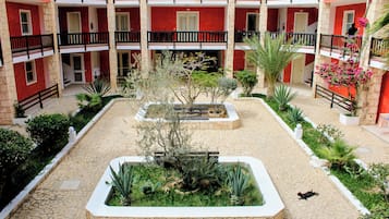 Un patio interior con un jardín central, rodeado por un edificio con balcones.
