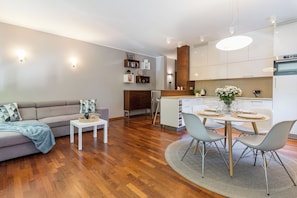 A modern living room with a sofa, a small table, and a dining area with chairs and a table set for four. - Imperial Apartments - Haffnera Residence (Sopot)