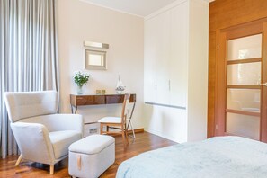 A hotel room with a bed, a chair, a small table with a vase of flowers, a mirror, and a wardrobe. - Imperial Apartments - Haffnera Residence (Sopot)