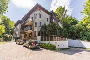 A multi-story residential building with balconies, parked cars, and lush greenery. - Imperial Apartments - Haffnera Residence (Sopot)