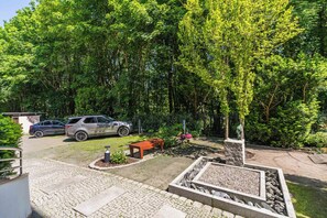 A parking area with two cars, a stone fire pit, and a bench. - Imperial Apartments - Haffnera Residence (Sopot)