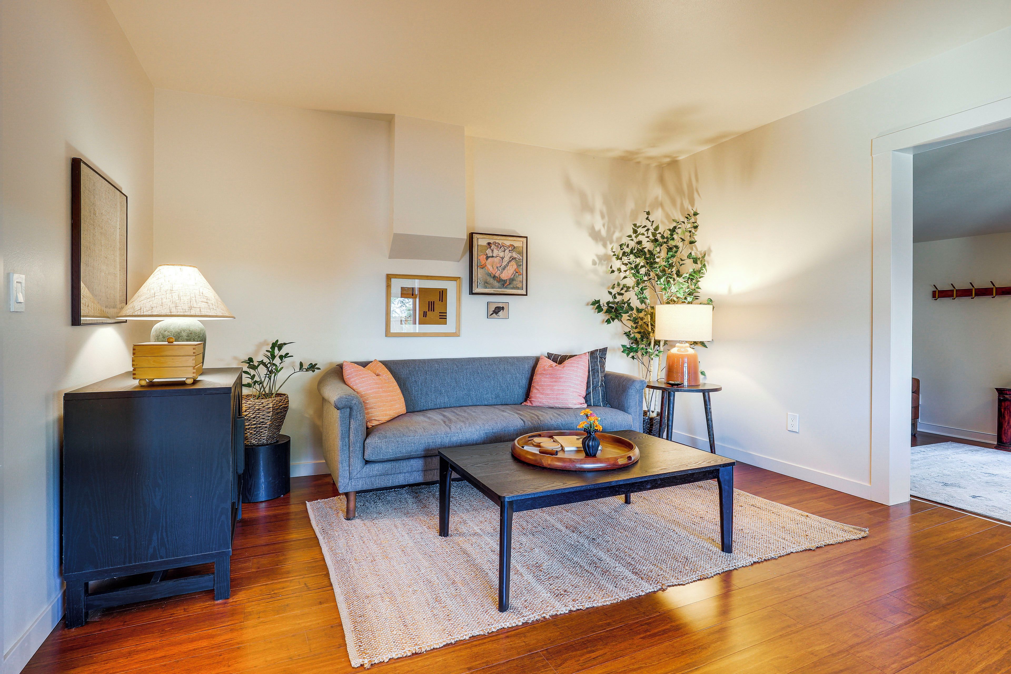 A living room with a sofa, coffee table, lamp, and artwork on the wall.