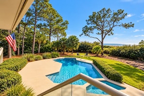 A swimming pool with a clear view of the ocean, surrounded by well-maintained landscaping and a flag. - 7 Brown Pelican | Expansive Oceanfront Sea Pines Retreat & Private Pool & Spa (Hilton Head Island)