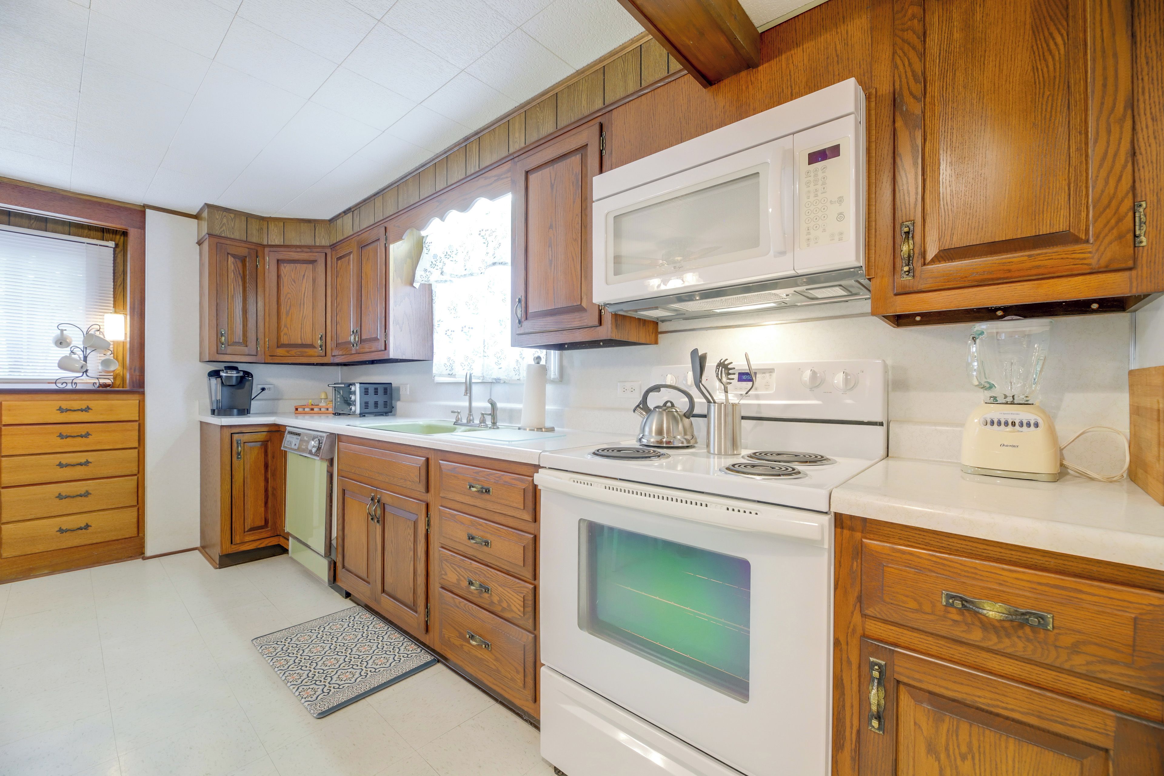 A kitchen with wooden cabinets, a microwave, a stove, and a coffee maker.