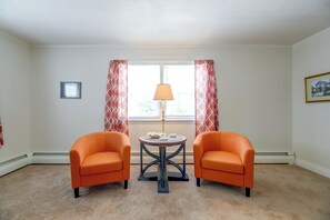 A room with two orange armchairs, a small round table with a lamp, and a window with patterned curtains. - Nanticoke River Area, Nature Lover's Paradise (Sharptown)