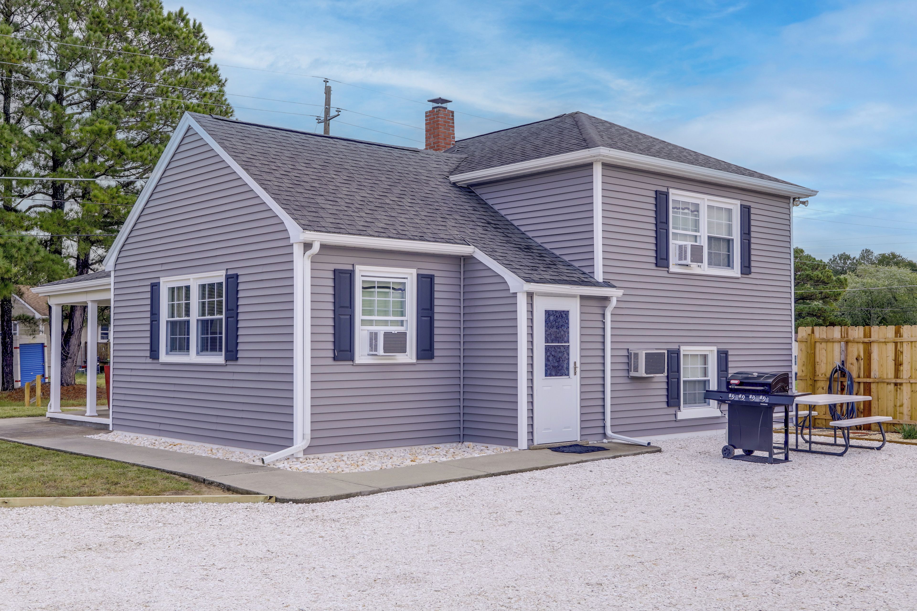 A two-story house with a covered porch, a garage, and a backyard with a grill and table.