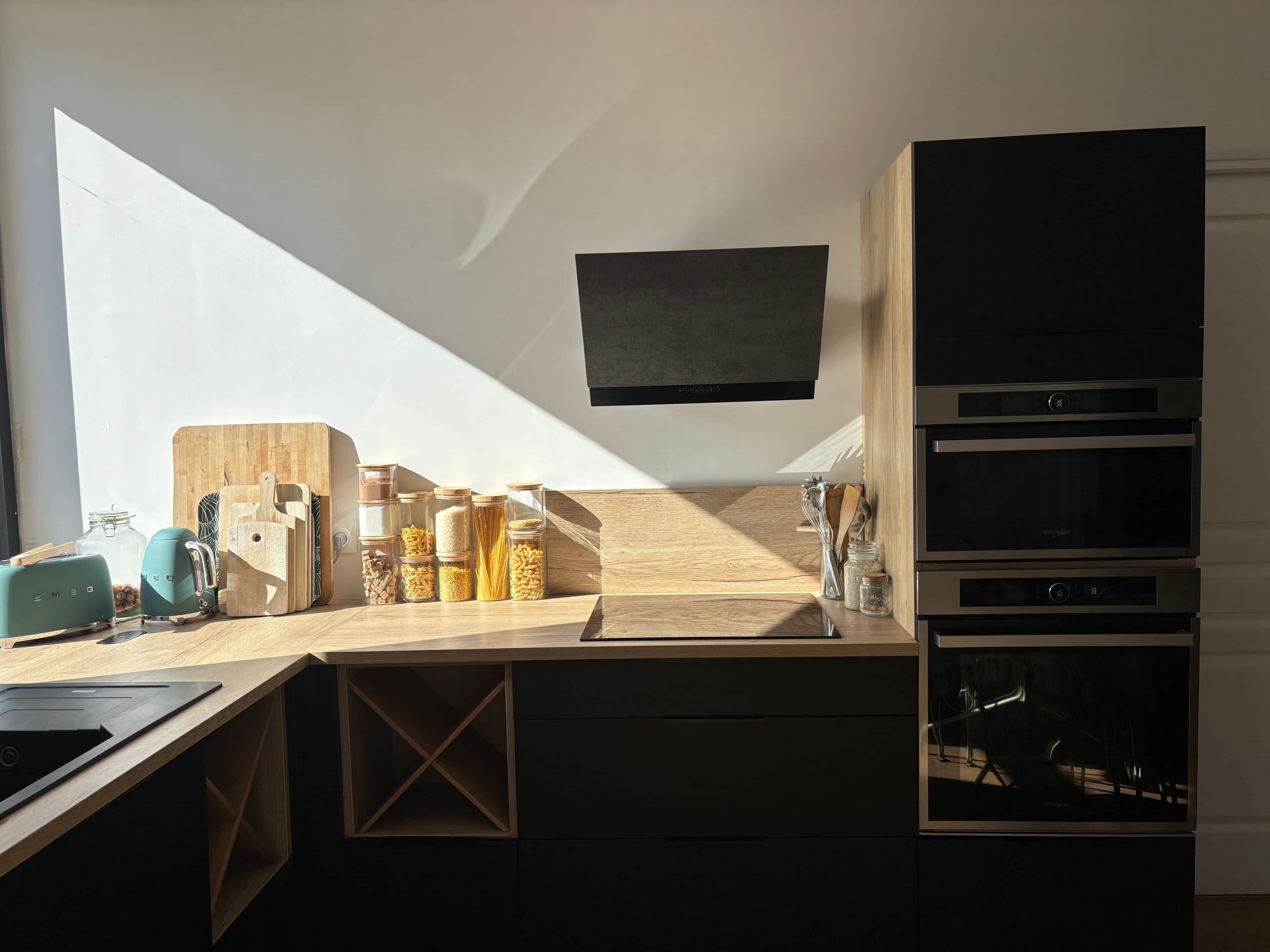 Una cucina moderna con forno a incasso, microonde e televisore a schermo piatto montato sopra il bancone.