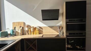 Una cucina moderna con forno a incasso, microonde e televisore a schermo piatto montato sopra il bancone.