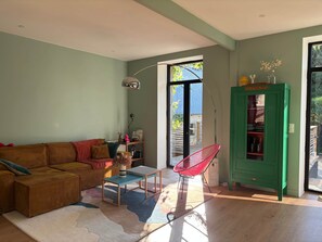 A living room with a sofa, a coffee table, a red chair, a green cabinet, and a large window.