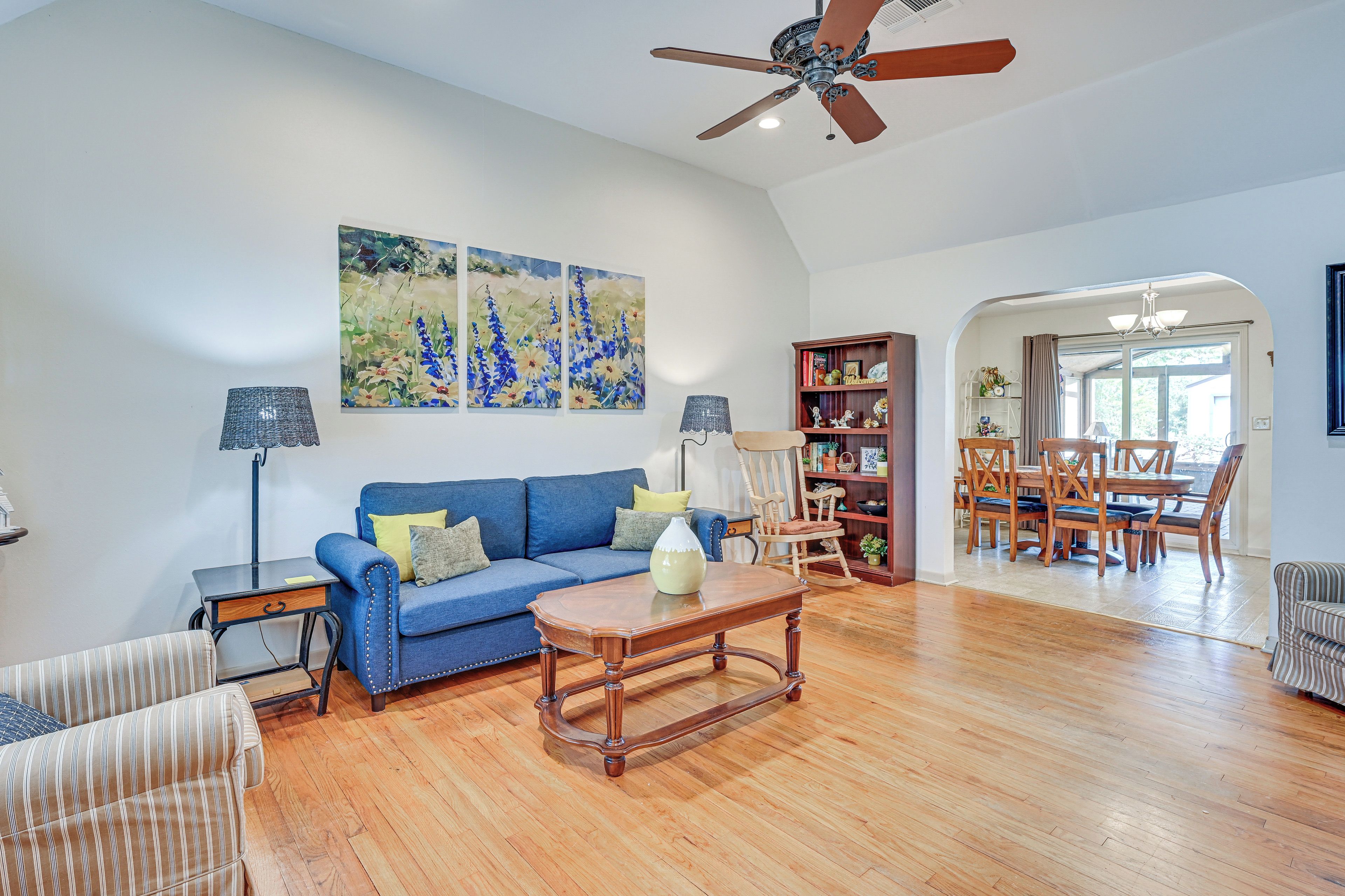 A spacious living room with a blue sofa, wooden coffee table, and a ceiling fan.