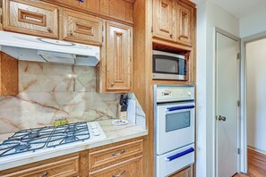 A kitchen with wooden cabinets, a gas stove, a microwave, and an oven. - Screened Porch! Aggieland Home Near Texas A&M (Bryan)